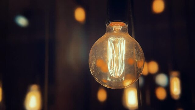 Flickering old fashion tungsten Edison light bulb lamp over black background. Slow motion shot 4K.