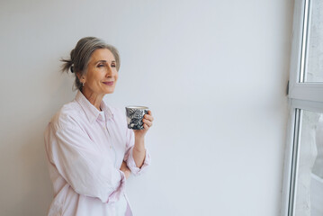 Portrait of elderly female in casual casual wear holding a mug