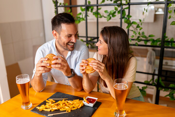 Couple eating burgers and drinking beer