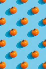 ripe whole persimmon on a blue background. Pattern. Vertical picture
