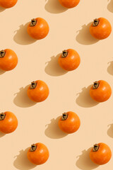 Fototapeta na wymiar ripe whole persimmon on a beige background. Pattern. Vertical picture