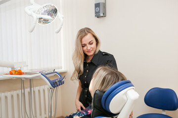 a dentist is a young white woman with blonde hair who is receiving a patient in a dental chair