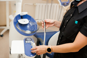 dentist a young white woman with blonde hair adjusts the equipment in the dental office