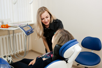 dentist a young white woman examines a patient a girl in a dental chair