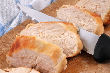 Blanc de poulet cuit tranché sur une planche à découper avec un couteau