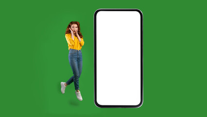 Shocked Woman Near Blank Cellphone Screen Jumping Over Green Background