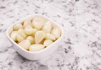 Tasty pickled garlic in the bowl. Canned garlic.