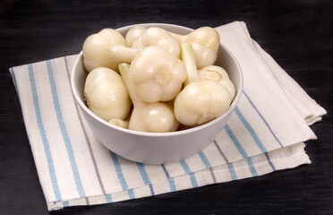 Tasty pickled garlic in the bowl. Canned garlic.