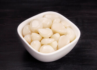 Tasty pickled garlic in the bowl. Canned garlic.