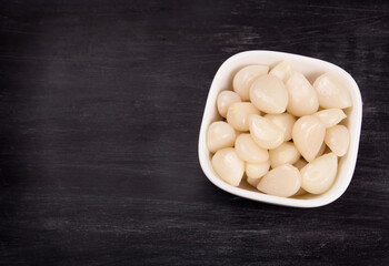 Tasty pickled garlic in the bowl. Canned garlic.