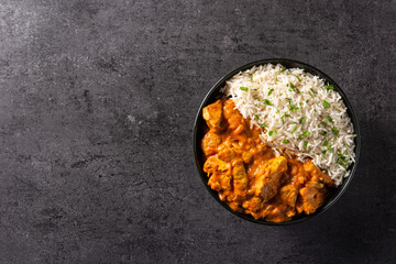 Indian butter chicken in black bowl on black background. Top view. Copy space