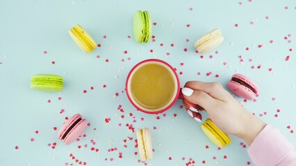 Top view of colorful cookies, French Macarons, and a cup of coffee on a pastel blue background with beautifully scattered confetti