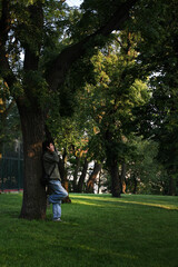 Fototapeta premium A man stands by a tree and talks on the phone