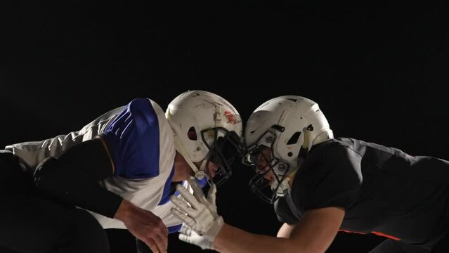 Collision Of Two American Football Players. Athletes In Helmet And Uniform On Black Background Of Arena. American Football Kickoff Game Start, Aggressive Face Off. Masculine Team Game In Slow Motion.