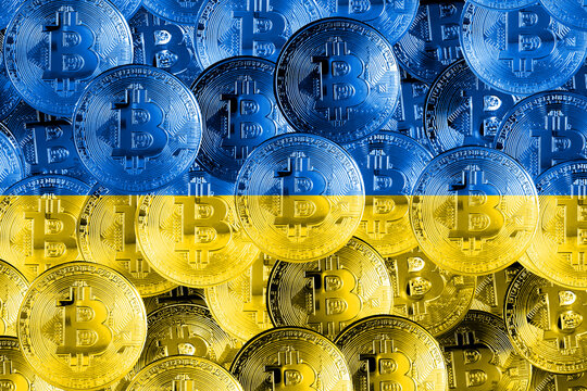 Holds a physical version of Bitcoin and the Ukrainian flag. Conceptual image of Ukraine's cryptocurrency and blockchain technology. Double exposure creative bitcoin symbol hologram.