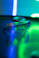 sunglasses lie on a round surface and sparkle in neon lights