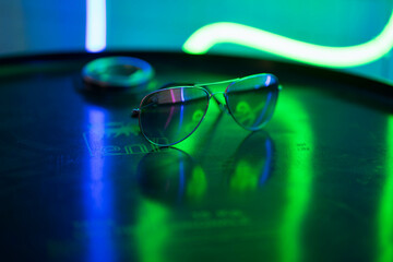sunglasses lie on a round surface and sparkle in neon lights