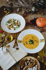 Autumn dishes: dumplings with walnuts, feta, honey and pear and pumpkin soup with seeds on a textured wooden table