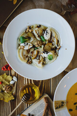 Autumn dishes: dumplings with walnuts, feta, honey and pear on a textured wooden table