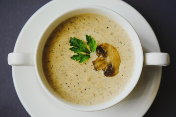 Mushroom cream soup in a white cup on a gray background