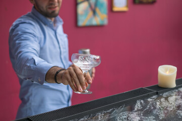 Bartender cools the glass with ice before making a cocktail. Close up photo, process, bar. High quality photo