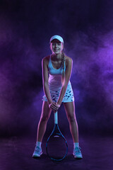 Fototapeta na wymiar Tennis player. Beautiful girl teenager and athlete with racket in sporswear and hat on tennis court with neon lights. Sport concept.