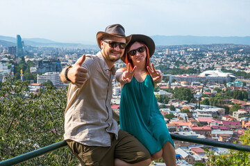 happy tourist couple taking with view in Tbilisi. Happy man and woman smiling in front of the cityscape panorama of the Capital of Georgia, travel concept