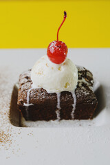Chocolate brownie muffins with a ball of ice cream and cherry with cinnamon and powdered sugar on a white plate