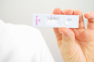 Female hand holding a plastic test for coronavirus close-up on white background.