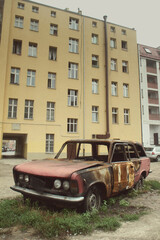 Abandoned, burned car in Western European city, wide shot