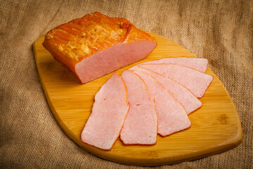 sliced ​​boiled pork on a wooden board on a brown background