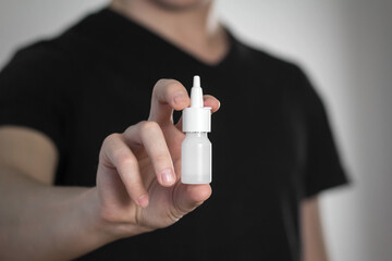 A man holds a spray for a runny nose. Close up