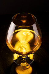 a glass of cognac on a black background