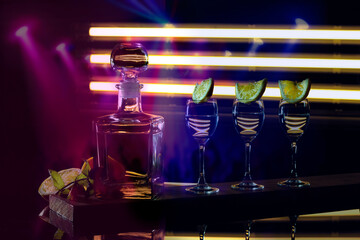 shot glasses with lime and vodka on a dark table of disco lights