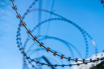 Barbed wire against the blue sky. Barbed fence close-up.