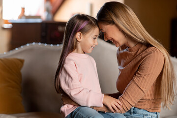 Portrait of happy woman and daughter hugging at home
