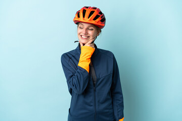 Young cyclist woman isolated on blue background looking to the side and smiling - obrazy, fototapety, plakaty