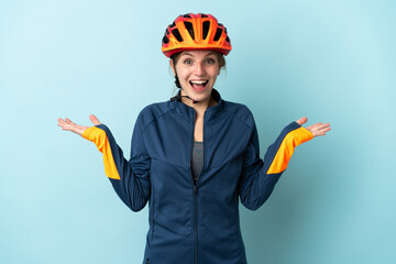 Young cyclist woman isolated on blue background with shocked facial expression - obrazy, fototapety, plakaty