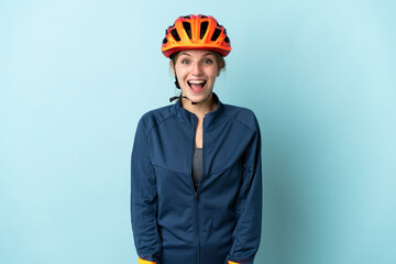 Young cyclist woman isolated on blue background with surprise facial expression - obrazy, fototapety, plakaty