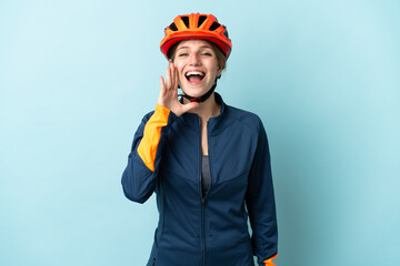 Young cyclist woman isolated on blue background shouting with mouth wide open