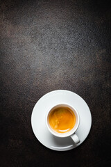 A cup of espresso coffee on a dark table, top view