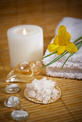 Fototapeta na wymiar Spa composition on table in wellness center. Towels, flower, seashells, and bath salt on bamboo mat.