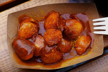 Cardboard box with ready to eat sliced curry sausage with red hot sauce and spice powder