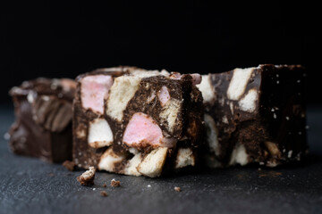 Rocky Road Chocolate with marshmallow, cake and biscuit close-up on a slate. Black background with...
