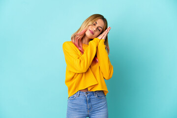 Young woman over isolated blue background making sleep gesture in dorable expression