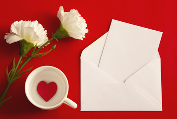 Flower and card with space for text on red background. Flat lay, top view
