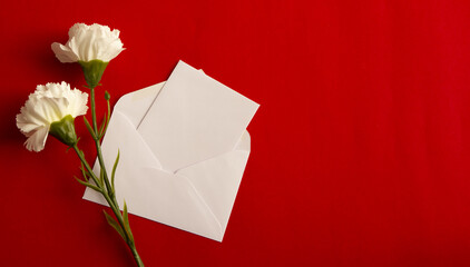 Flower and card with space for text on red background. Flat lay, top view	