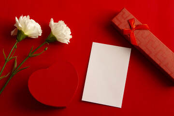 Flowers, heart, gift and blank card for text  on red background. Flat lay, top view	
