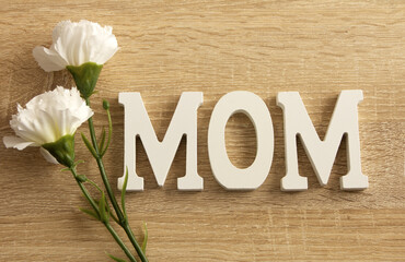 Happy Mother's Day.  Mom letters and flowers on wooden background. Flat, top view.