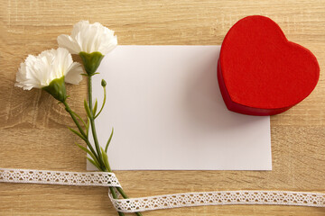 Flowers, heart and card with space for text on wooden background. Flat, top view